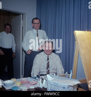 Deutscher Showmaster und Entertainer Hans Joachim Kulenkampff in der Maske, links hinten Martin Jente, Deutschland 1960er Jahre. Deutsche entertainer Hans Joachim Kulenkampff erhält seine Make-up und Frisur vor eine TV-Show, Hintergrund links Martin Jente, Deutschland der 1960er Jahre. Stockfoto