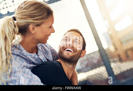 Paar an jedem Anderen, lächelnden Frau auf Mans zurück Stockfoto