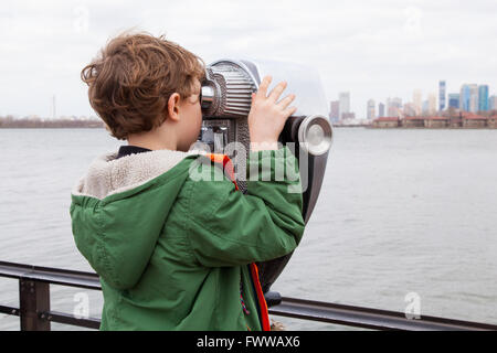 Sechs Jahre alter Junge mit Münzeinwurf Fernglas auf Liberty Island, New York, Vereinigte Staaten von Amerika. Stockfoto