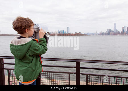 Sechs Jahre alter Junge mit Münzeinwurf Fernglas auf Liberty Island, New York, Vereinigte Staaten von Amerika. Stockfoto