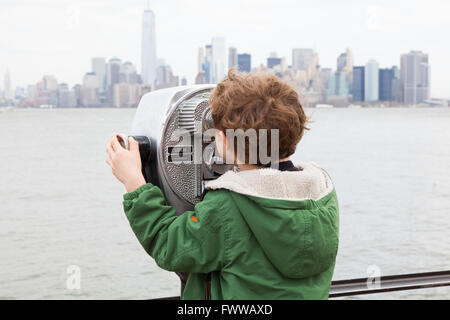 Sechs Jahre alter Junge mit Münzeinwurf Fernglas auf Liberty Island, New York, Vereinigte Staaten von Amerika. Stockfoto
