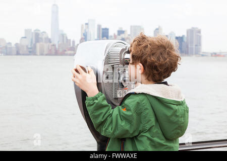 Sechs Jahre alter Junge mit Münzeinwurf Fernglas auf Liberty Island, New York, Vereinigte Staaten von Amerika. Stockfoto