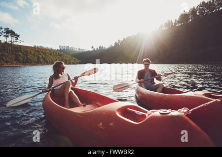 Junges Paar Kajakfahren auf dem See zusammen an einem Sommertag. Mann und Frau Kanu an einem sonnigen Tag. Genießen einen Tag am See. Stockfoto