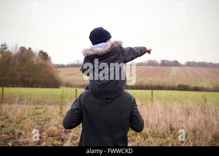 Vater gibt Sohn Fahrt auf Schultern während Landschaft zu Fuß Stockfoto