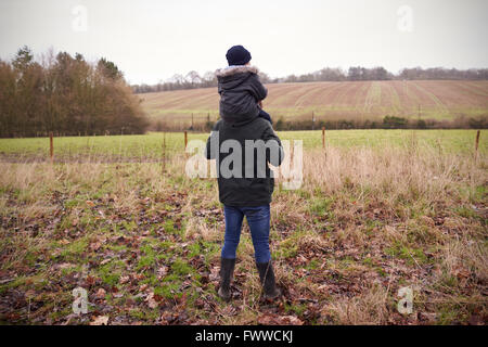 Vater gibt Sohn Fahrt auf Schultern während Landschaft zu Fuß Stockfoto