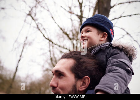 Vater gibt Sohn Fahrt auf Schultern während Landschaft zu Fuß Stockfoto