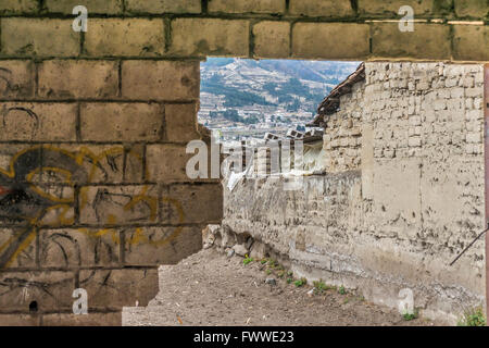 Nahaufnahme des gebrochenen Ziegelmauer und Armenhäuser im Hintergrund in einem Dorf Außenseiten Otavalo Stadt in Ecuador. Stockfoto