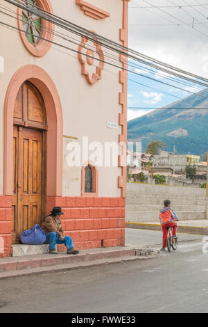 OTAVALO, ECUADOR, Oktober - 2015 - indigenen Mann sitzt und Kinder Fahrrad auf der Straße in die Straße Schlepptau Trocal De La sierra Stockfoto