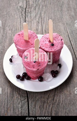 Schwarze Johannisbeere Eis am Stiel in Plastikbechern auf hölzernen Hintergrund gemacht Stockfoto