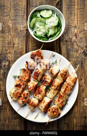 Hähnchenspieße und Gurkensalat auf hölzernen Hintergrund, Ansicht von oben Stockfoto