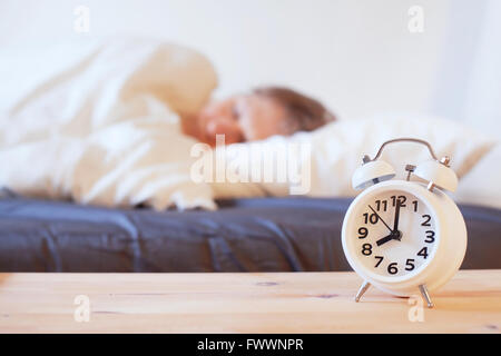 Wachen Sie am Morgen mit Wecker, Person schlafend im Bett auf Stockfoto