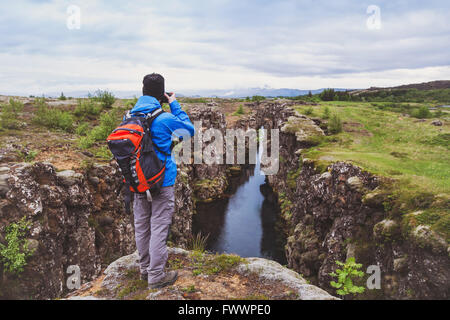 Naturfotograf, Wanderer mit Rucksack, die Aufnahme der schönen Landschaft in Island Nationalpark Thingvellir Stockfoto