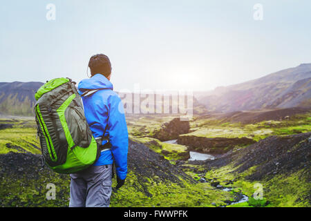 Wanderer mit Rucksack genießen schöne Panoramablick auf Berge in Island, Vulkanlandschaft, Reise-Hintergrund Stockfoto