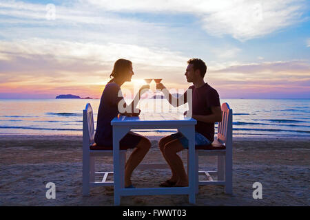 romantisches Abendessen am Strand im Luxusrestaurant, paar auf Hochzeitsreise, trinken tropische Cocktails bei Sonnenuntergang Stockfoto