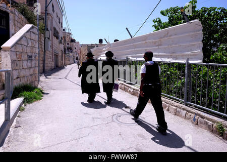 Jerusalem, Israel. April 2016. Zwei ultra-orthodoxe religiöse Juden werden von zwei bewaffneten Sicherheitsleuten durch das palästinensische Viertel Silwan oder Siloam begleitet, das sich an den Hängen südlich der alten Stadtmauer in Ostjerusalem Israel befindet Stockfoto