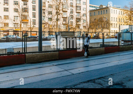 Erste warme Tag in Moskau, Russland. 8. April 2016. Erste wirklich warme Tag des Frühlings in Moskau. Die Temperatur +14 C (57,2 F), klarer Himmel, Luftfeuchtigkeit ca. 48 % und kein Wind machte den Tag wirklich warm und angenehm. Unbekannter Mann fährt entlang der Pokrowski (Fürbitte der Heiligen Jungfrau)-Boulevard mit dem Einzelrad elektrische Scooter. Er trägt einen Kampf Panzerhelm. Die Baustelle hinter ihm ist tot. Alle Werke sind unterbrochen, weil ein Keller von der alten Stadtmauer entdeckt wurde. Das historische Artefakt ist unter Schutzabdeckung von weißer Farbe. Bildnachweis: Alex Bilder/Alamy Live-Nachrichten Stockfoto