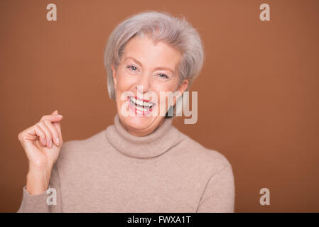 Porträt von einer älteren Frau vor braunem Hintergrund Stockfoto