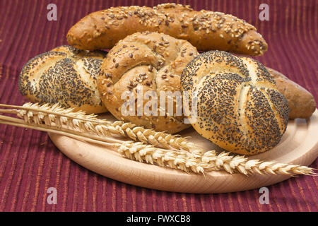 Verschiedene Arten von Vollkornbrot und Ähren auf einem Holzbrett liegen. Stockfoto