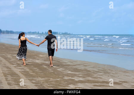 Paar am Strand spazieren. Junge glückliche interracial paar zu Fuß am Strand und lächelnd zu einander. Asiatische Frau, kaukasischen Mann Stockfoto