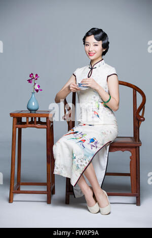 Junge schöne Frau im traditionellen Cheongsam Tee trinken Stockfoto