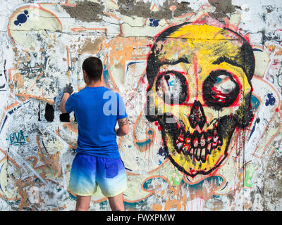 Graffitikünstler sprühen über alte Graffiti an der Wand in Spanien Stockfoto