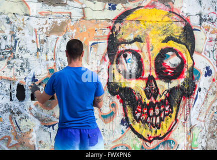 Graffitikünstler sprühen über alte Graffiti an der Wand in Spanien Stockfoto