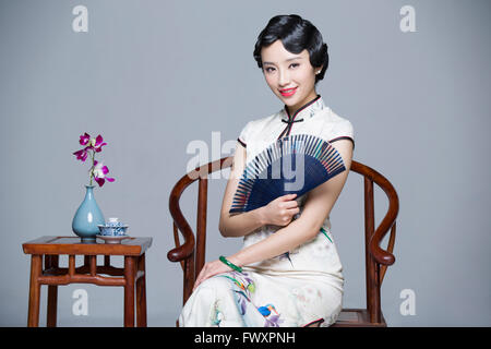 Junge schöne Frau im traditionellen Cheongsam mit klappbarer Ventilator Stockfoto