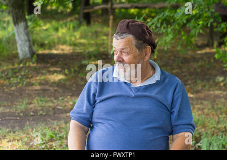 Outdoor Portrait lächelnd senior bärtigen in einem Baum Schatten Stockfoto
