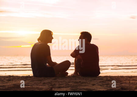 Mann und Frau am Strand bei Sonnenuntergang, junge Paar sprechen in der Nähe von das Meer, dating oder Freundschaft Konzept Stockfoto