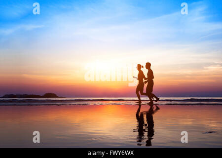 Training-Hintergrund, zwei Menschen, Joggen am Strand bei Sonnenuntergang, Läufer Silhouetten, gesunden Lebensstil-Konzept Stockfoto