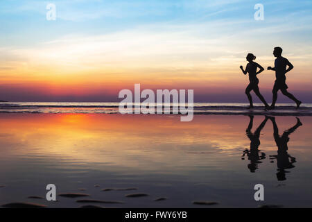 zwei Läufer am Strand, Silhouette des Menschen Joggen im Sonnenuntergang, gesunden Lebensstil Hintergrund mit Exemplar Stockfoto