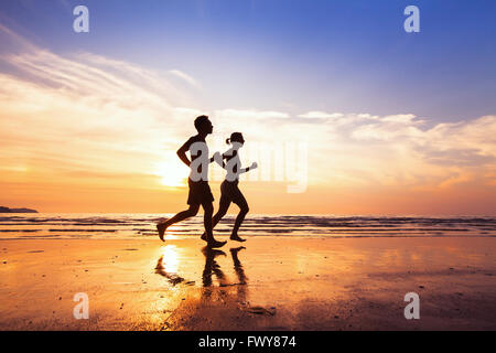 Sport und gesunde Lebensweise, zwei Menschen, Joggen am Strand bei Sonnenuntergang Stockfoto