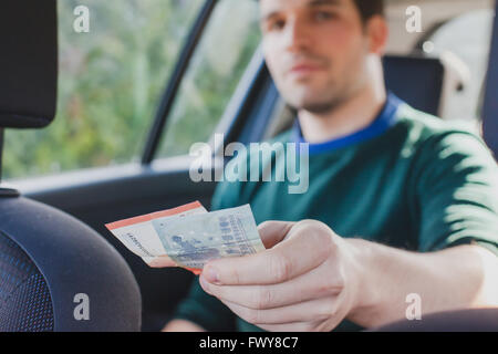 bezahlen Sie mit Bargeld im Taxi, Nahaufnahme der Hand des Passagiers, Geld an die Fahrer im Auto Stockfoto