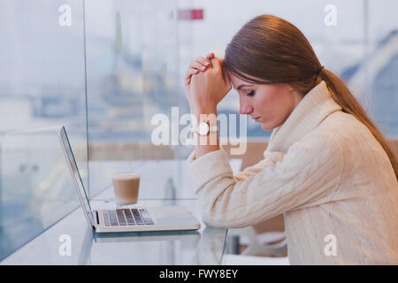 Arbeitslosigkeit-Konzept, Problem, traurig müde Frau vor Laptop innen moderne helle café Stockfoto