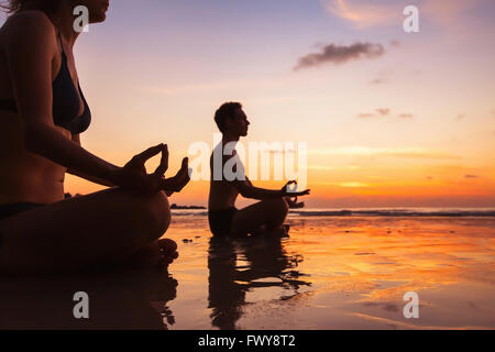 Gruppe von Menschen, die meditieren auf dem Strand, Yoga und Gesundheit Hintergrund Stockfoto