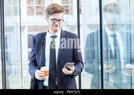 Jungunternehmer im Flughafen gehen und e-Mails auf smartphone Stockfoto