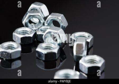 Mehrere weibliche Metallschrauben mit Reflektion auf schwarzem Hintergrund. Stockfoto