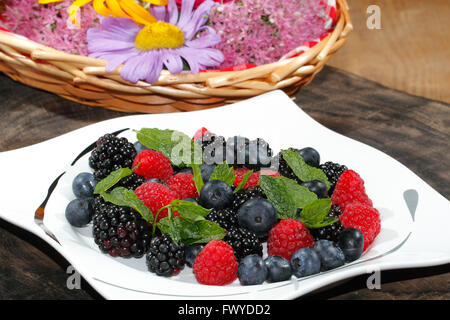 Heidelbeeren, Himbeeren, Brombeeren, garniert mit Minze auf einem Teller Stockfoto