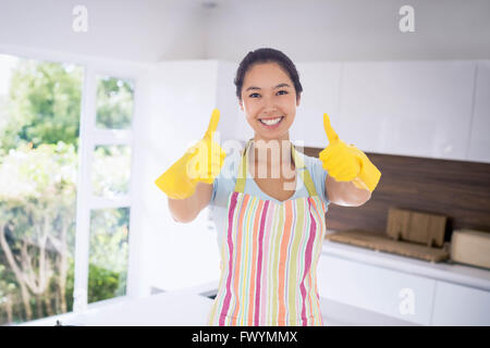 Zusammengesetztes Bild glücklich Frau Daumen aufgeben in Gummihandschuhe Stockfoto