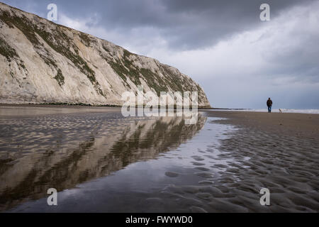 Ein Mann geht seinen Hund an Yaverland Strand in Sandown Bay Stockfoto