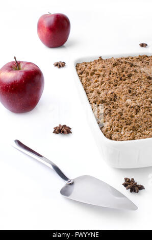 Weiße Wanne mit Crubmle, zwei rote Äpfel, Badian und Kuchen Server isoliert auf weißem Hintergrund. Stockfoto