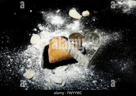 Lebkuchen Herz Stillleben mit Mandeln und Mehl auf schwarzem Hintergrund isoliert. Stockfoto