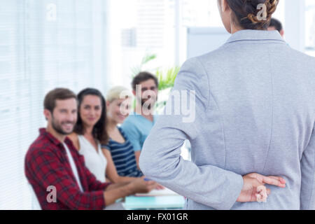 Zusammengesetztes Bild der Geschäftsfrau mit Daumen hinter ihrem Rücken auf weißem Hintergrund Stockfoto