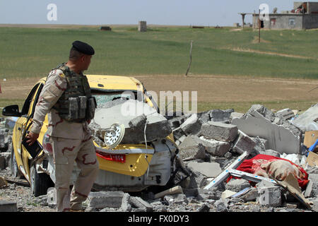 Mosul, Irak. 9. April 2016. Ein Soldat der irakischen Armee Kraft steht in der Nähe eines zerstörten Autos in Khrbadan Dorf in der Stadt Qayyarah, 55 km südlich von Mosul, Irak, am 9. April 2016. © Yaser Jawad/Xinhua/Alamy Live-Nachrichten Stockfoto