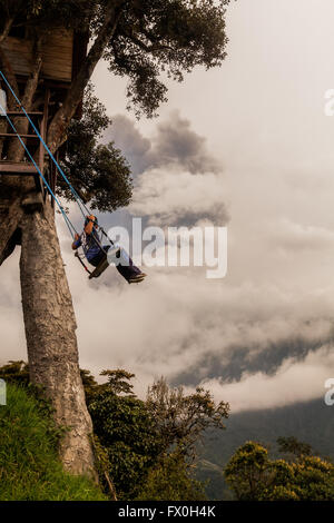 Banos De Agua Santa - 8. März 2016: glückliches Kind schwingen auf einer Schaukel bei Sonnenuntergang, Blick vom Casa Del Arbol, Baumhaus, Tun Stockfoto