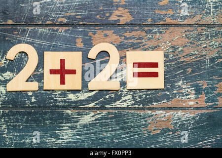 Einfache mathematische Gleichung, 2 plus 2, auf rustikalen Holzoberfläche Stockfoto