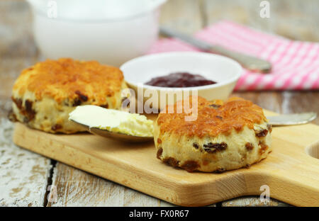 Englische Scones mit Rosinen auf Holzbrett, Clotted Cream und Marmelade Stockfoto