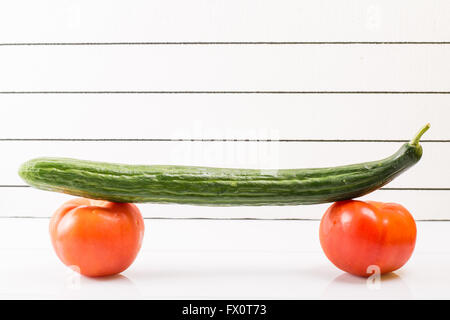Konzeptbild von skateboarding und gesunde Ernährung. Zwei Tomaten mit Gurken Stockfoto