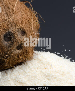 Haufen Dehydriertes Coconut und ganze Kokosnuss auf schwarzem Hintergrund isoliert. Stockfoto