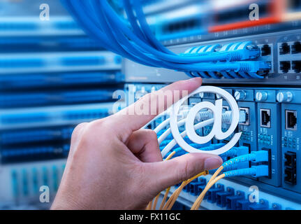 Hand, die e-Mail-Symbol über Netzwerk-Switch und Ethernet-Kabel, Daten-Center-Konzept. Stockfoto